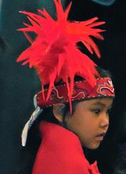 A young boy wearing a red headdress.